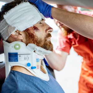 A man with a neck brace receiving a head check after a head injury - Diaz-Granados Law Firm